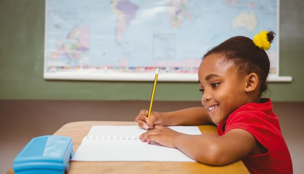 Cute little girl writing book in classroom — Stock Photo, Image