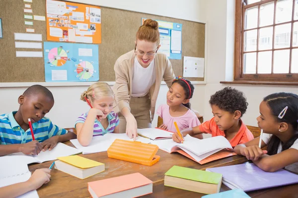 Pretty teacher helping pupils in classroom — Stock Photo, Image