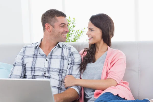 Casal olhando um para o outro enquanto usando laptop — Fotografia de Stock