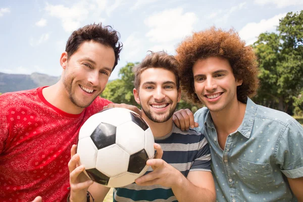 Счастливые друзья в парке с футболом — стоковое фото