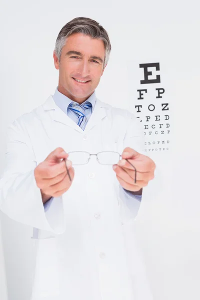 Optometrist holding eyeglasses out — Stock Photo, Image