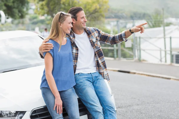 Pareja sonriente apoyada en el capó — Foto de Stock