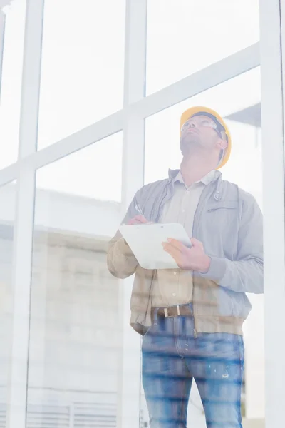 Supervisor looking up while writing on clipboard — Stock Photo, Image