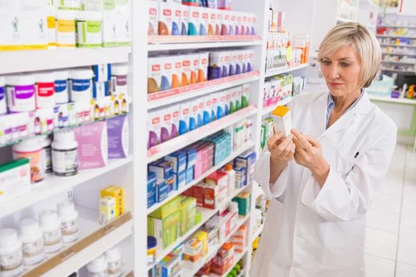 Smiling pharmacist looking at medicine — Stock Photo, Image