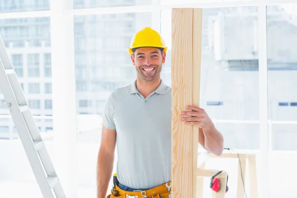Smiling male carpenter holding plank — Stock Photo, Image