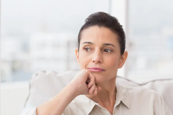 Nachdenkliche Frau sitzt auf Sofa — Stockfoto