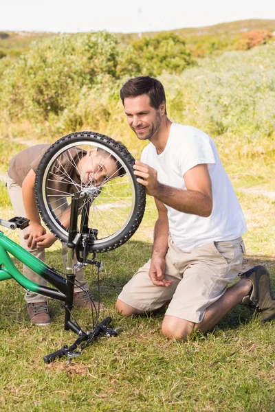 Padre e hijo reparando la bicicleta juntos — Foto de Stock