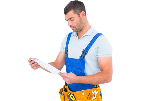 Male carpenter in overalls reading clipboard — Stock Photo, Image