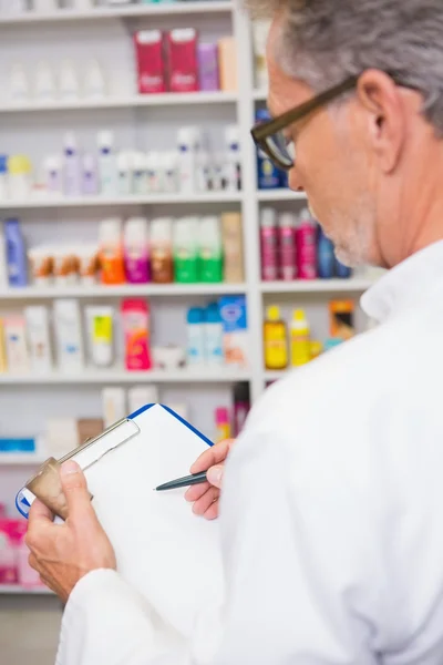 Senior pharmacist writing on clipboard — Stock Photo, Image