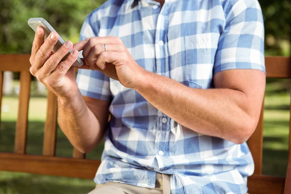 Man zit op bankje met telefoon — Stockfoto