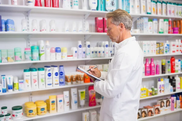 Senior pharmacist writing on clipboard — Stock Photo, Image