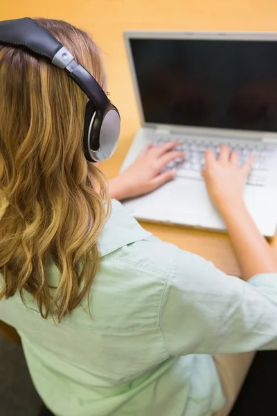 Jolie étudiante étudiant à la bibliothèque avec ordinateur portable — Photo