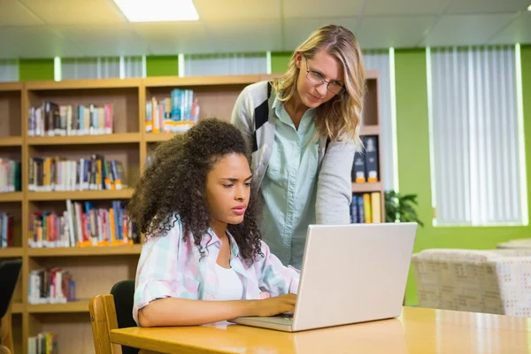 Estudiante recibiendo ayuda de tutor en la biblioteca — Foto de Stock