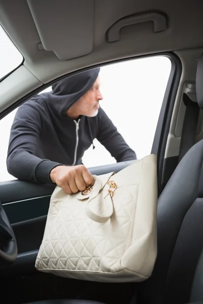 Thief breaking into car and stealing hand bag — Stock Photo, Image