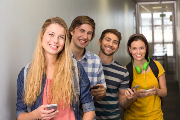 Students with cellphones at college corridor — Stock Photo, Image