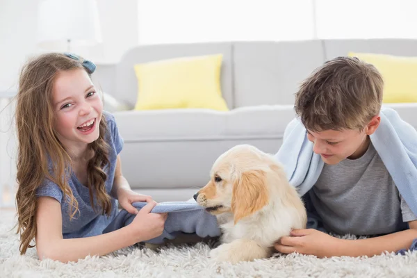 Syskon leker med valpen på matta — Stockfoto