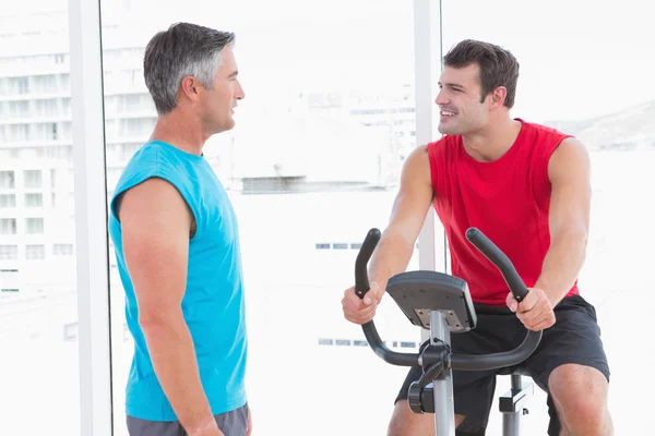 Trainer met man op hometrainer — Stockfoto