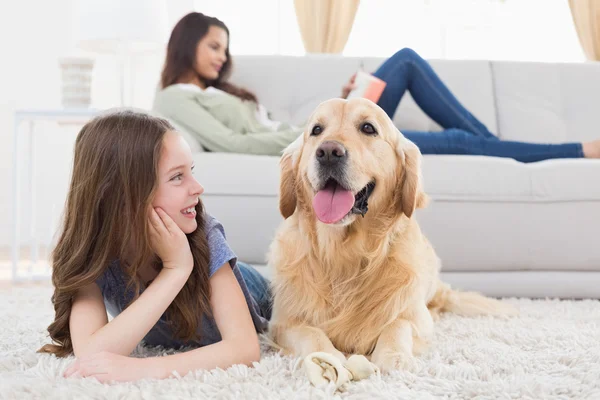 Girl looking at dog while lying on rug — Stock Photo, Image