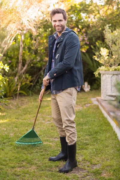 Hombre guapo rastrillando en su jardín — Foto de Stock