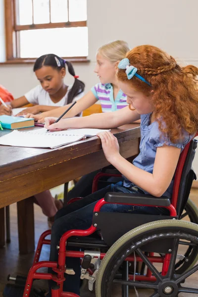 Schattig leerlingen schrijven op Bureau in klas — Stockfoto