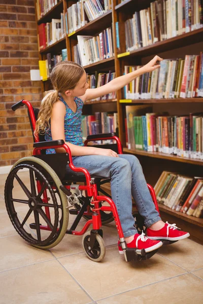 Mädchen im Rollstuhl sucht Buch in Bibliothek aus — Stockfoto