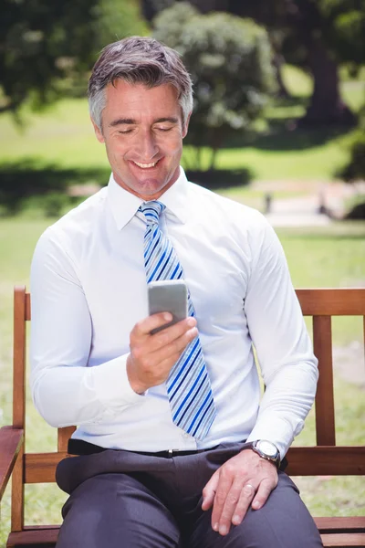 Affärsman med sin telefon i parken — Stockfoto