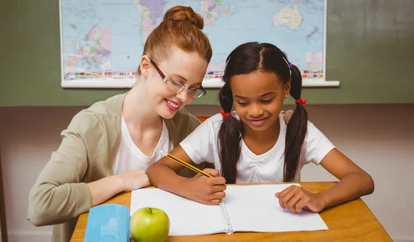 Leraar bijstaan meisje met huiswerk in klas — Stockfoto