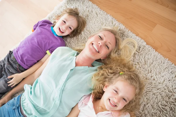 Gelukkig moeder en kinderen liggen op tapijt — Stockfoto