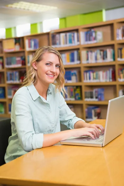 Söt student som studerar i biblioteket med laptop — Stockfoto