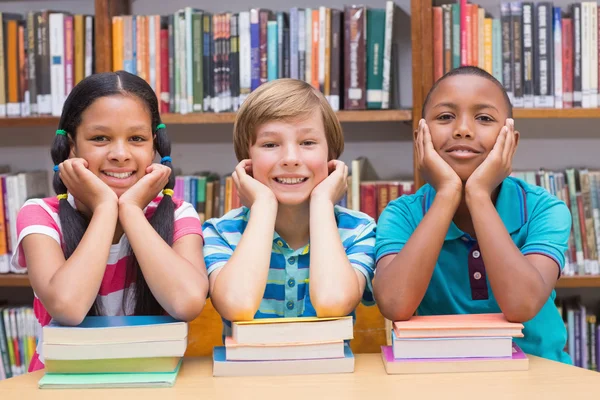 Söta elever tittar på kameran i biblioteket — Stockfoto