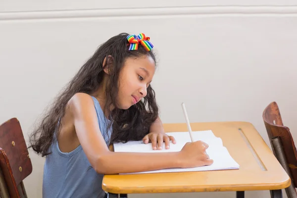 Симпатичные ученики пишут за столом в классе — стоковое фото