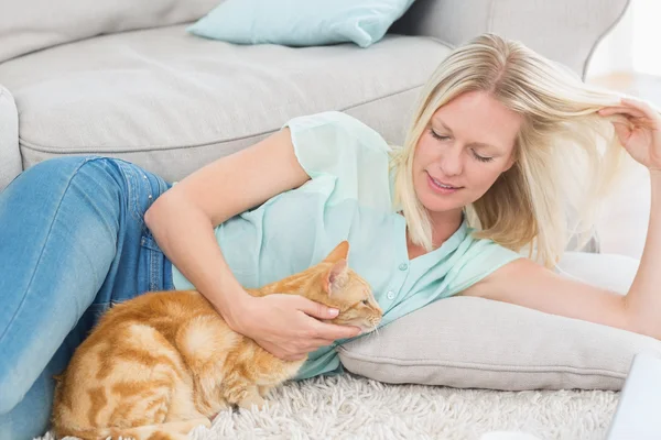 Mujer acariciando gato mientras jugando con pelo en alfombra —  Fotos de Stock