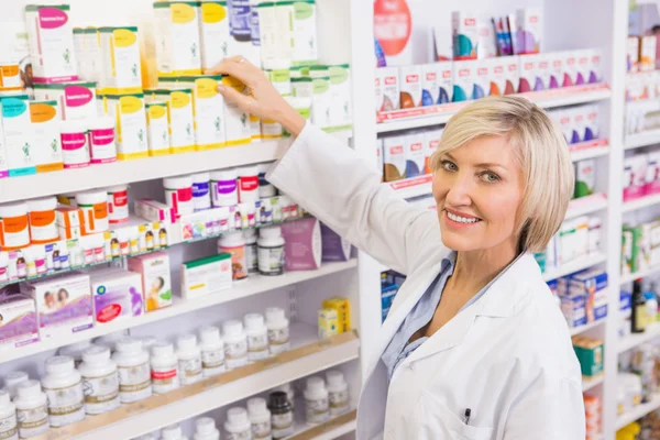 Farmacêutico sorrindo levando caixa de prateleira — Fotografia de Stock