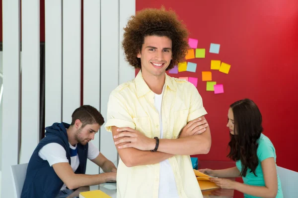 Casual young man with arms crossed in office — Stock Photo, Image