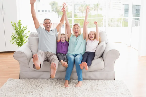 Семья с поднятыми руками на диване — стоковое фото