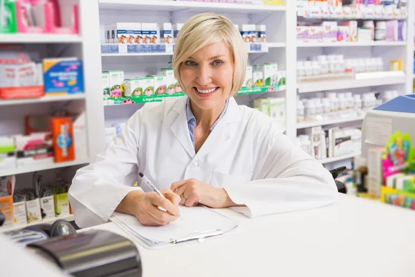 Farmacêutico sorridente escrevendo na área de transferência — Fotografia de Stock