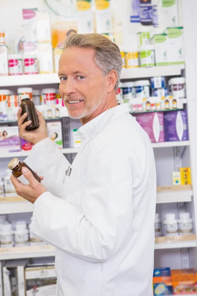 Farmacêutico sênior tomando frasco de prateleira — Fotografia de Stock