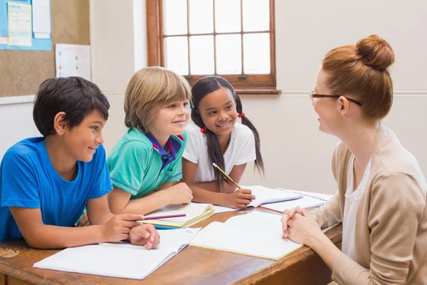 Teacher and pupils working at desk together — Stock Photo, Image