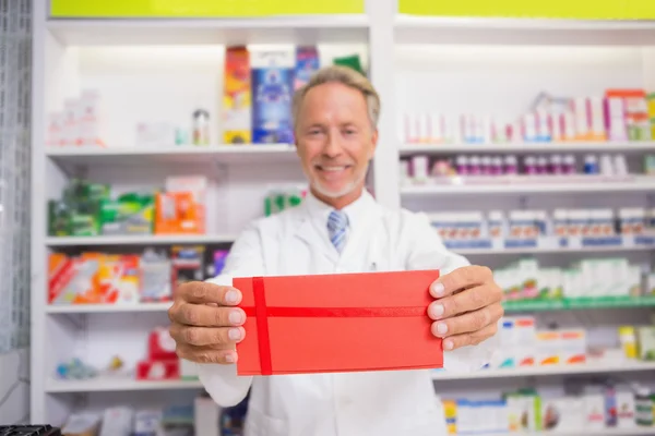 Smiling senior pharmacist presenting paper — Stock Photo, Image