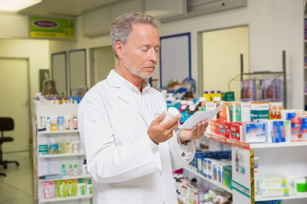 Pharmacist reading prescription and holding medicine — Stock Photo, Image