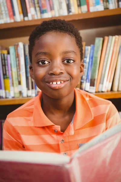 Bonito menino leitura livro na biblioteca — Fotografia de Stock
