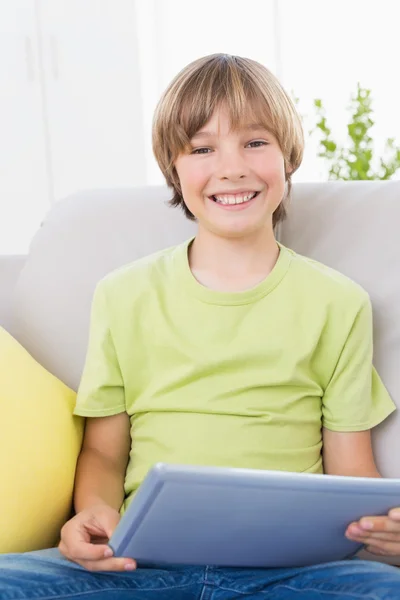 Niño feliz usando la tableta digital en el sofá — Foto de Stock