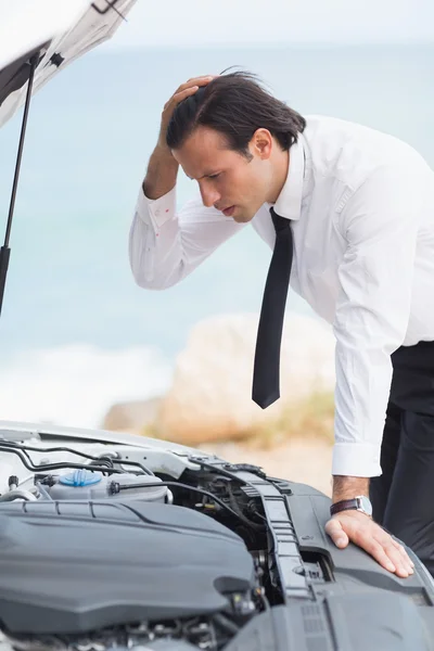 Stressed businessman looking at engine — Stock Photo, Image