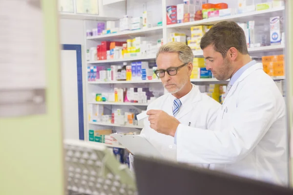Farmacêutico sênior lendo uma prescrição na área de transferência — Fotografia de Stock