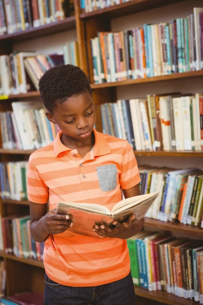 Bonito menino leitura livro na biblioteca — Fotografia de Stock