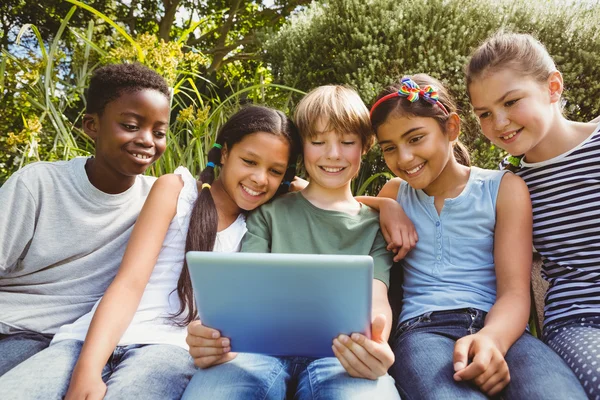 Crianças felizes usando tablet digital no parque — Fotografia de Stock