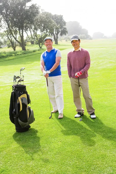 Golffreunde lächeln in Kamera mit Schlägern — Stockfoto