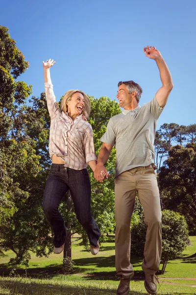 幸せなカップルが公園でジャンプ — ストック写真