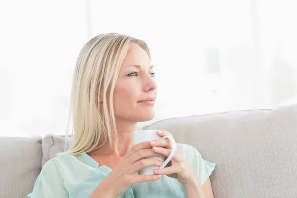 Mujer sosteniendo la taza de café mientras mira hacia otro lado — Foto de Stock