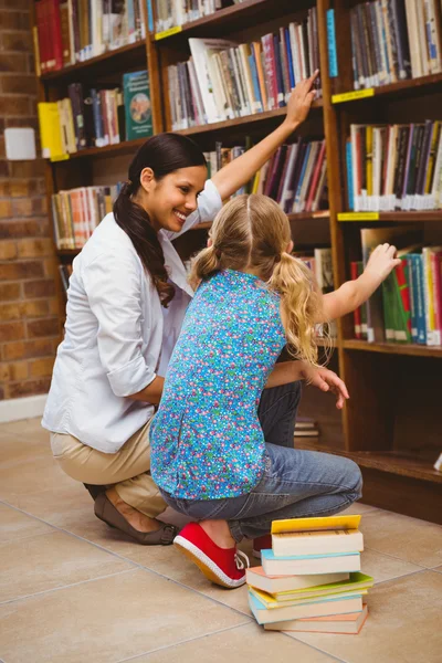 Enseignant et petite fille sélectionnant le livre dans la bibliothèque — Photo